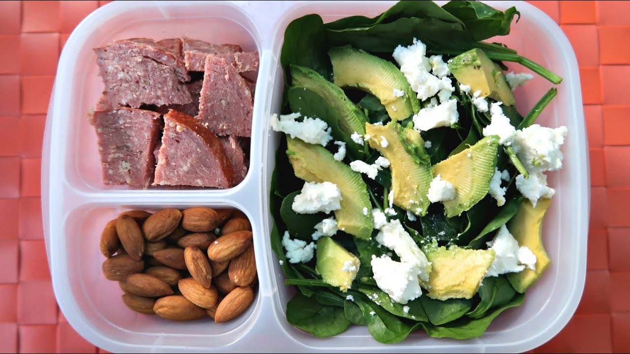 Low carb lunch box with spinach, avocado, feta, salami and almonds