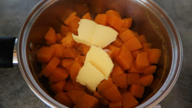 Adding butter and cream to the cooked easy sweet potato mash