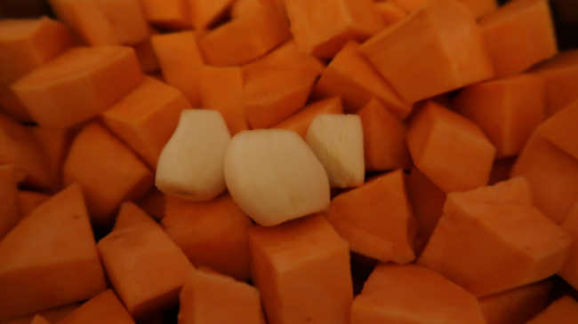 Adding garlic to the chopped sweet potatoes