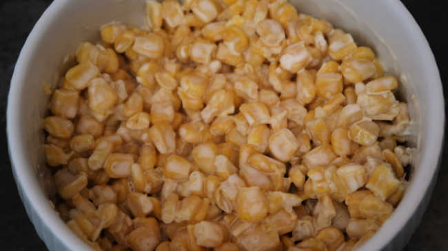 Creamy corn salad ingredients mixed together in a bowl