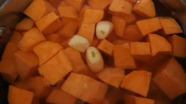 Garlic and sweet potatoes covered with water in the pot