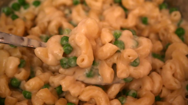 Spoon of macaroni cheese with peas