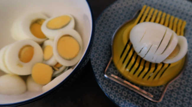 Hard-boiled eggs in a bowl and sliced