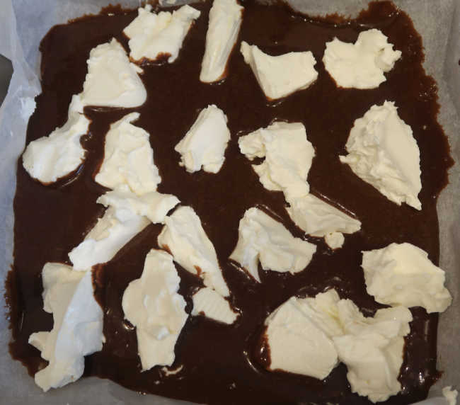Adding chopped cream cheese to the brownies